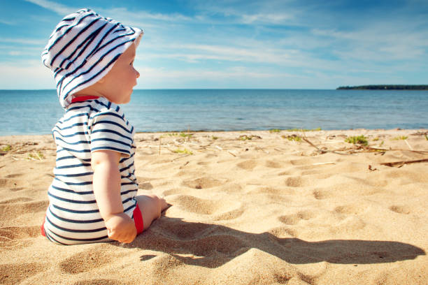 istock Little baby boy sitting on the beach in summer day 528567698