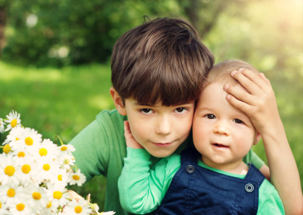 istock Two lovely brothers sitting in park with flowers 528567856