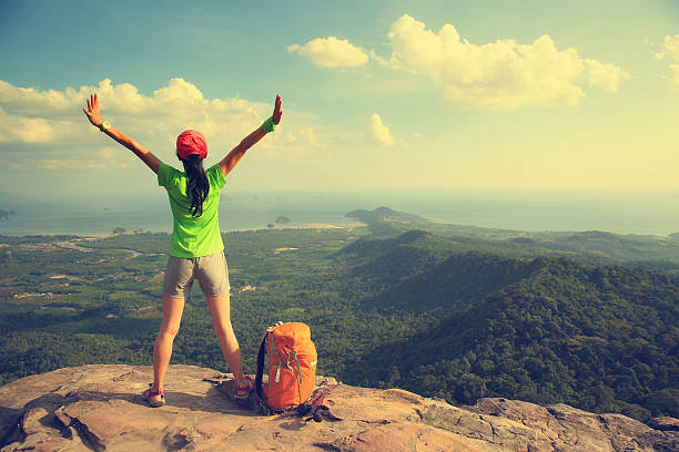 istock cheering successful woman hiker open arms at mountain peak 528568038