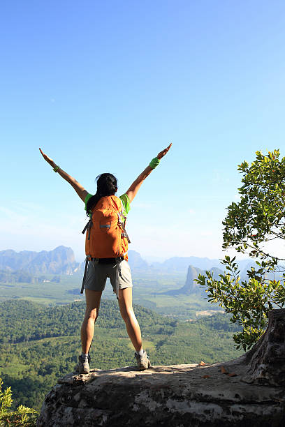 istock cheering successful woman hiker open arms at mountain peak 528568536