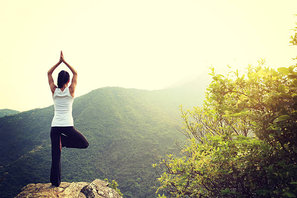 istock young woman practice yoga at mountain peak cliff 528570108