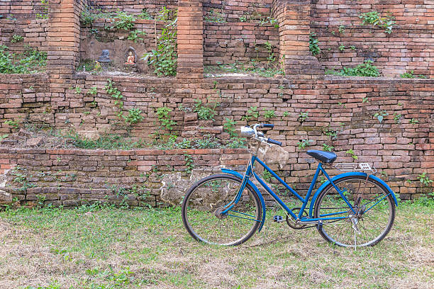 Munich, Germany - Dec 21, 2023 - Vintage bike with basket and Electric longtail cargo bike are parked side of Mounted burial headstones based upon the outside Old brick wall of the Munich Frauenkirche or Frauenplatz (Cathedral Church of Our Lady) in Munich. Space for text, Selective focus.