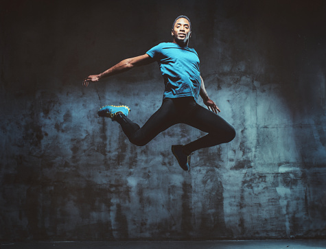 Full body shot of man jumping in the air in urban studio