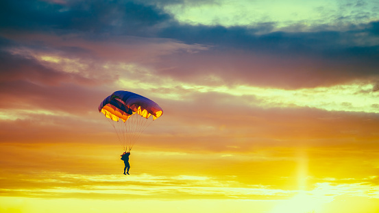 Skydiver On Colorful Parachute In Sunny Sunset Sky. Active Hobbies