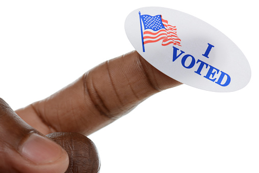 African American pointing with an “I voted” sticker stuck to his finger.