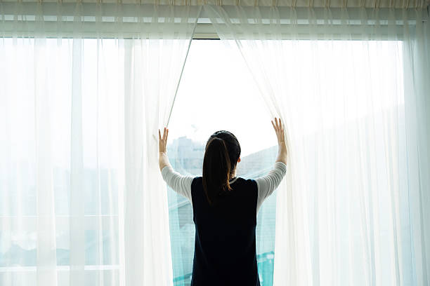 istock Young woman opening curtains 528583172