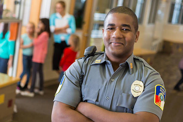 Friendly school security guard working on elementary school campus Friendly school security guard working on elementary school campus security staff stock pictures, royalty-free photos & images