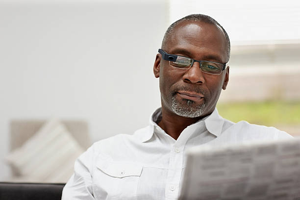 istock Mature african man wearing smart glasses reading newspaper 528586813