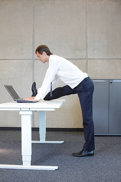 istock business man stretching leg in standing position at desk 528589017