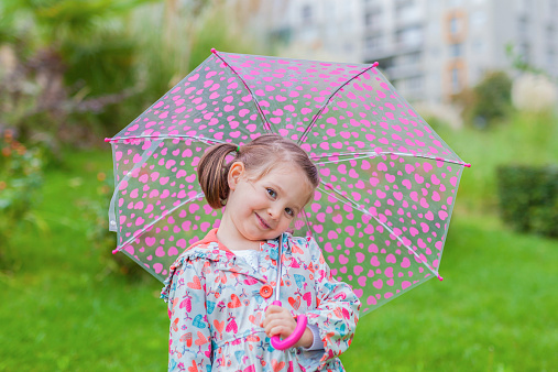 closeup photograph of smiling liitle cute girl with her umbrella in park