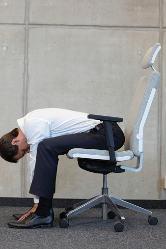 yoga with chair in office - business man exercising in office