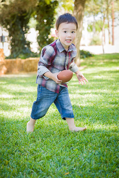 istock Cute Young Mixed Race Boy Playing Football Outside 528632017