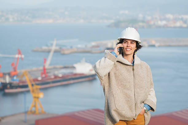 mulher na porto com capacete de segurança falando no telefone - industrial ship dock worker engineer harbor - fotografias e filmes do acervo