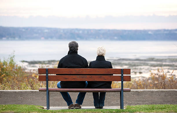 istock Mature couple sitting on park bench overlooking river. 528633468
