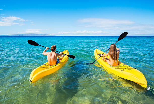 Man and Woman Kayaking in the Ocean Couple Kayaking in the Ocean on Vacation kayaking stock pictures, royalty-free photos & images