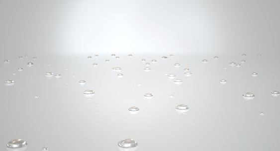A collection of various size droplets of water on a reflective white surface on an isolated white background