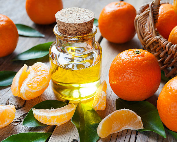 Bottle of essential citrus oil and ripe tangerines with leaves stock photo