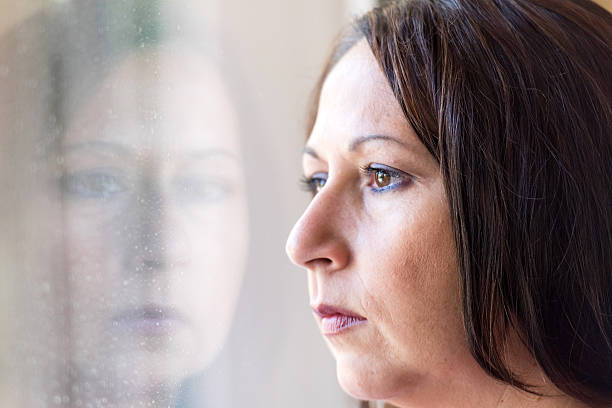 Pensive woman Pensive hispanic mature woman looking through a window deportation stock pictures, royalty-free photos & images