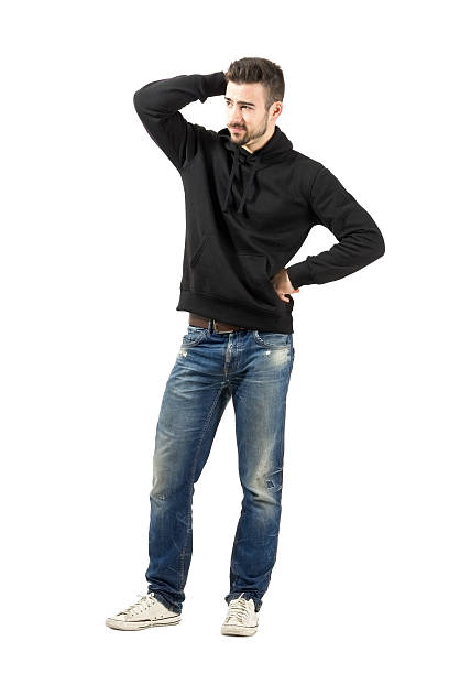 Thoughtful young man scratching head looking away Thoughtful young man scratching head looking at distance. Full body length portrait isolated over white background. worried man standing stock pictures, royalty-free photos & images