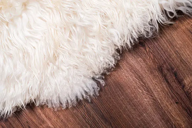 Decorative fur carpet on wood floor background