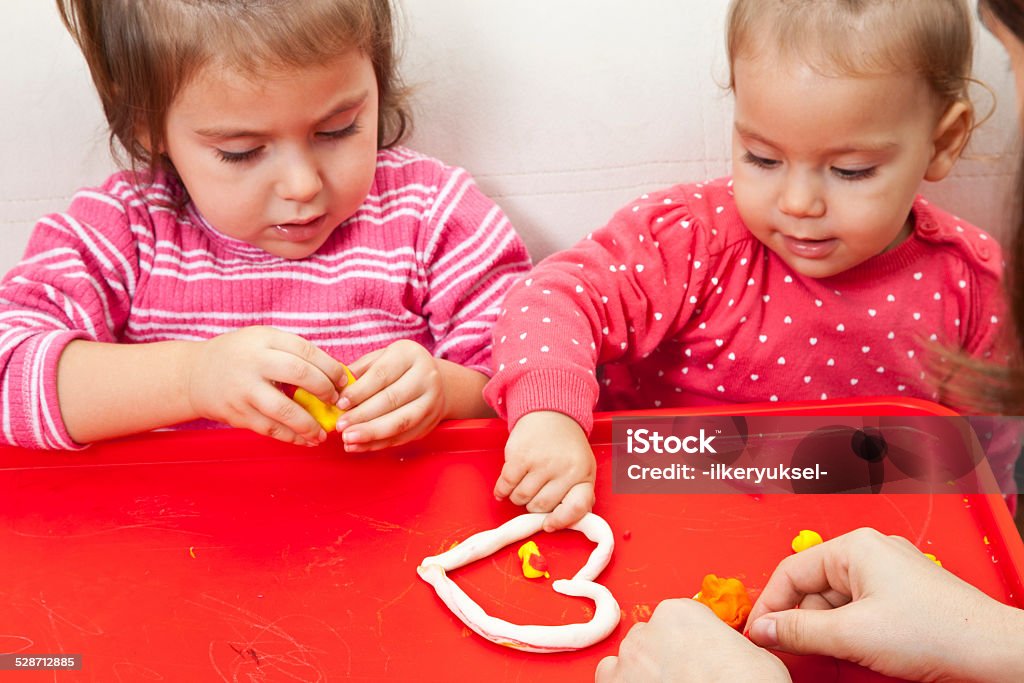 Girl playing with play dough Little girl is learning to use colorful play dough in a well lit room near window 12-17 Months Stock Photo