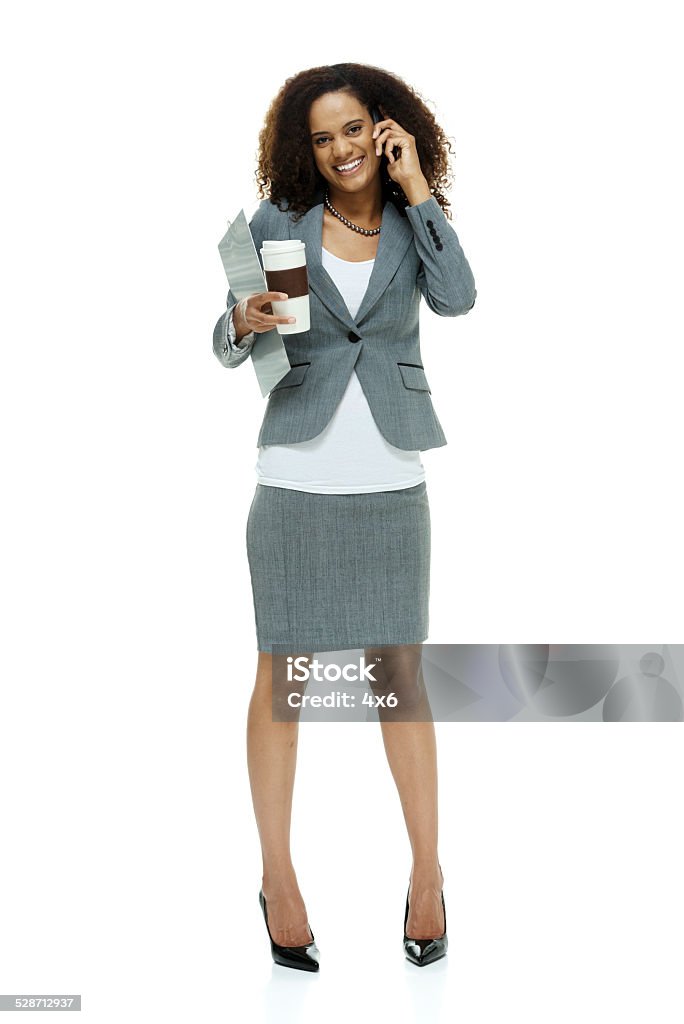 Happy businesswoman on mobile & holding coffee cup Happy businesswoman on mobile & holding coffee cuphttp://www.twodozendesign.info/i/1.png 20-29 Years Stock Photo