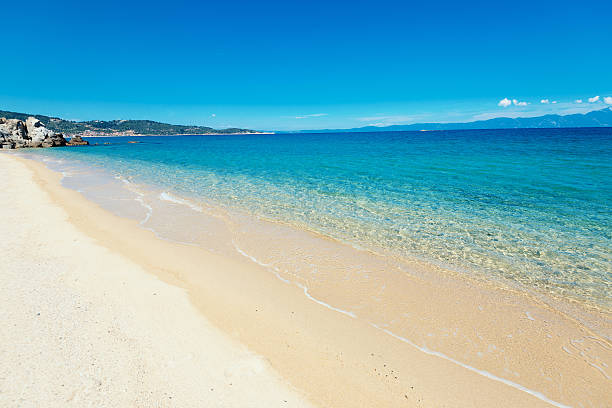 Sandy beach in summertime, near the waving ocean in Halkidiki, Greece with turquoise sea color on sunny summer day with no people and lots of copy space.
