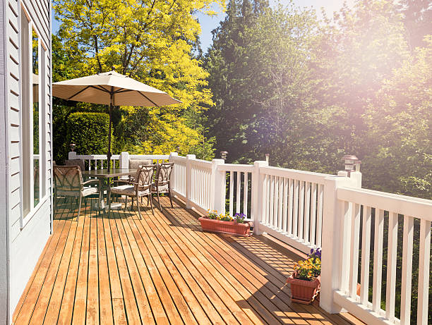 Bright daylight falling on home outdoor deck Afternoon bright daylight on outdoor home cedar deck with furniture and open umbrella. Light effect applied to image. Horizontal layout. cedar porch stock pictures, royalty-free photos & images
