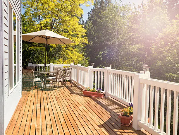 Afternoon bright daylight on outdoor home cedar deck with furniture and open umbrella. Light effect applied to image. Horizontal layout.