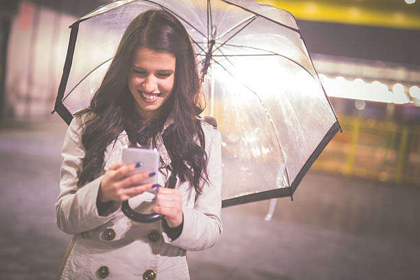 istock Woman with umbrella and smart phone 528716698