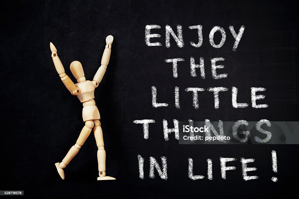 Enjoy the little things in life Wooden puppet and  blackboard with text ,, Enjoy the little things in life!"  Abstract Stock Photo