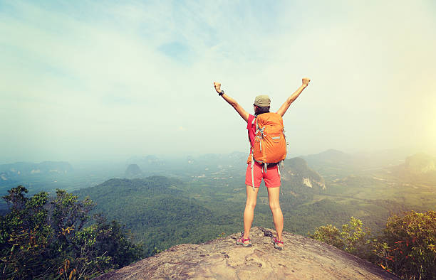 istock cheering successful woman hiker open arms at mountain peak 528718940