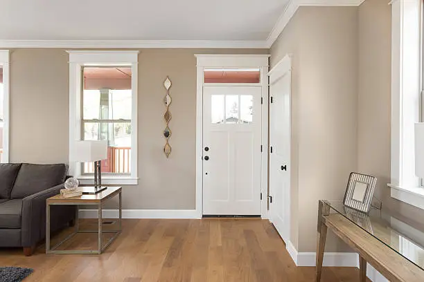 Entryway with hardwood floors, couch, lamp, and several windows