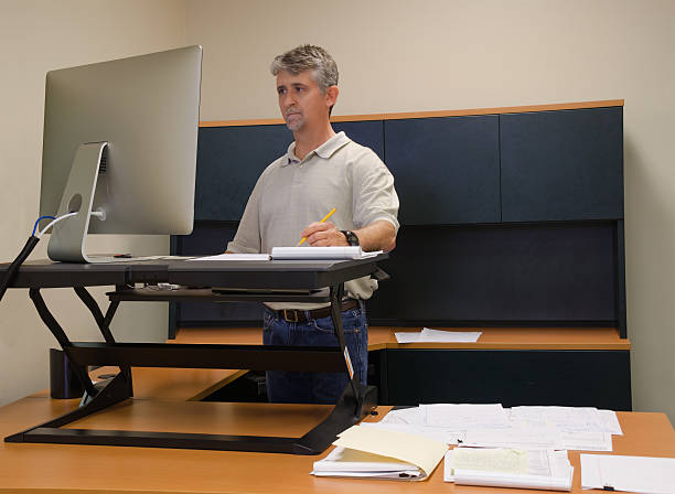 mann mit stand schreibtisch in büro für gute gesundheit - ergonomical stock-fotos und bilder