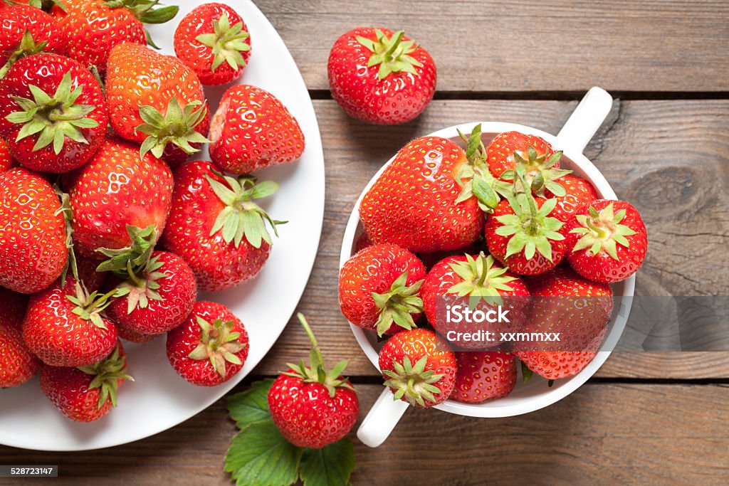 Strawberries on old wooden table Close up of strawberries in bowl on old wooden table. This file is cleaned and retouched. Above Stock Photo