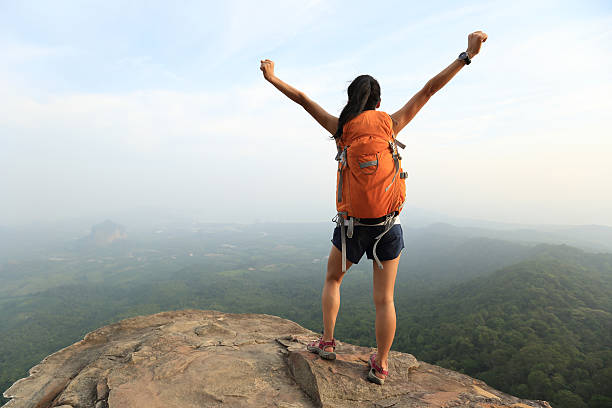 istock cheering successful woman hiker open arms at mountain peak 528725280
