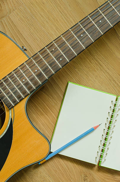 istock Acoustic Guitar and Notebook with wood background 528727155