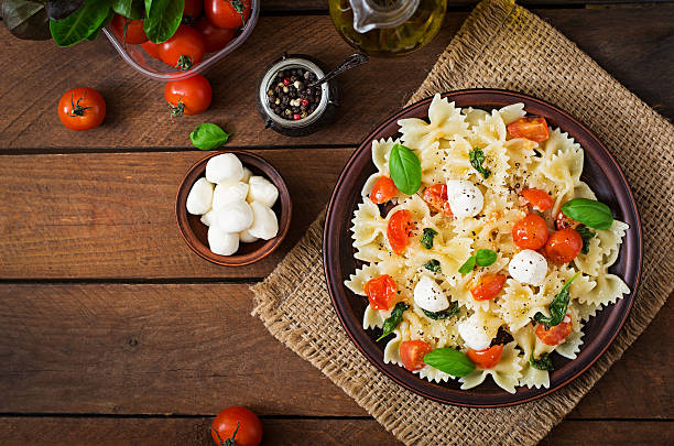farfalle pasta-caprese insalata con pomodori, mozzarella e basilico. - caprese salad foto e immagini stock