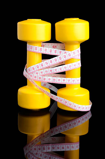 dos amarillo, mancuernas y cinta métrica colocarse vertical con referencia - gym yellow muscular build dumbbell fotografías e imágenes de stock