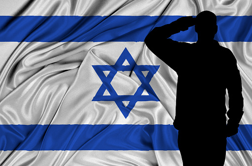 Silhouette of Israel soldier saluting to Israel flag