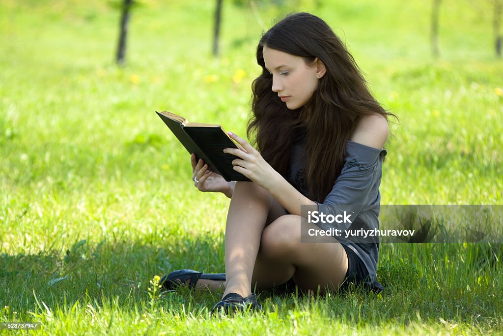 Young student reading book on meadow Adult Stock Photo