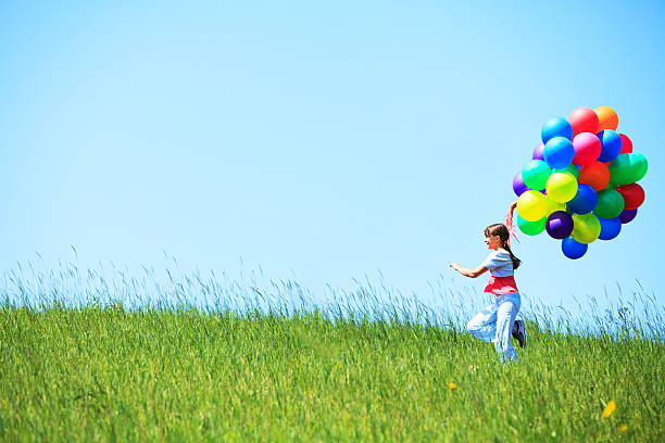 istock Girl running on the field with balloons 528740582