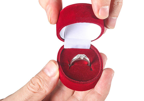 istock Man's hand holding engagement ring isolated on white 528741407