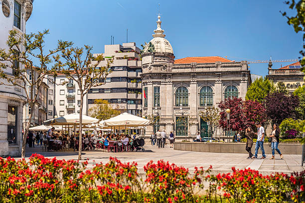 Braga city centre square and outdoor restaurant Braga, Portugal - May 1, 2016: Braga city centre square and outdoor restaurant. People seen eating outdoors under the parasols in the city square. Buildings and colonial architecture seen in the background with tourists walking around. braga portugal stock pictures, royalty-free photos & images