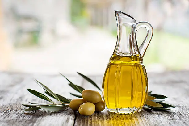 Olive oil and olive branch on the wooden table outside