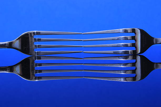 Forks Reflecting on Blue Background stock photo