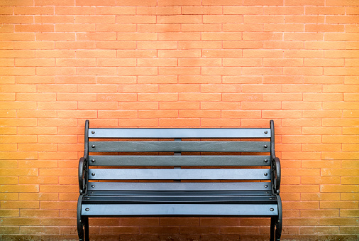 Black bench in front of variant color processed brick wall