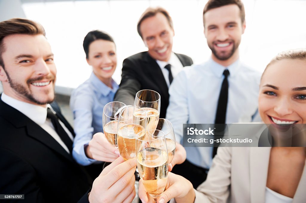 Toasting to success. Group of business people toasting with champagne and smiling while standing close to each Achievement Stock Photo