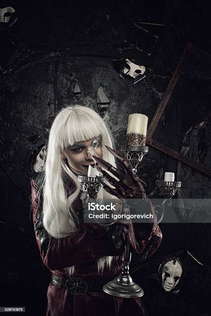 Keeper of the room of crying masks Horrible old-fasioned lord with cursed hand and candles posing in a dark room Adult Stock Photo