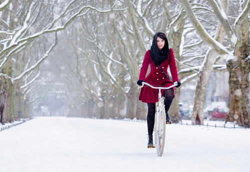 beautiful girl on bike at snow, winter biking at park